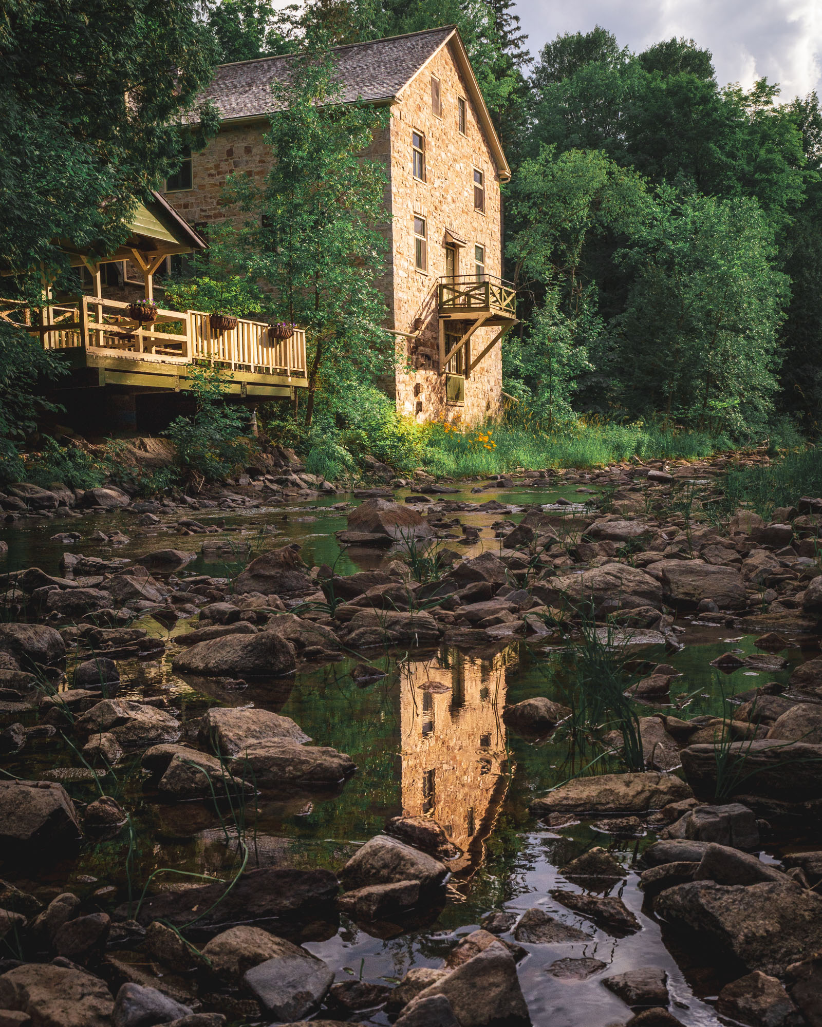 An old mill sitting on a small body of rocky water